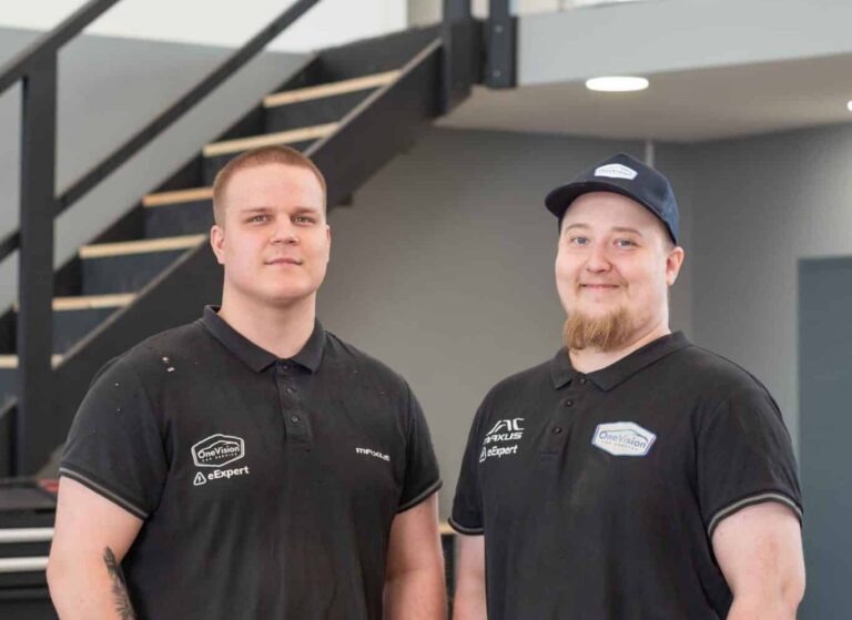 OneVision Car Service autohuolto modernissa autokorjaamossa, taustalla renkaita ja huoltokalustoa.