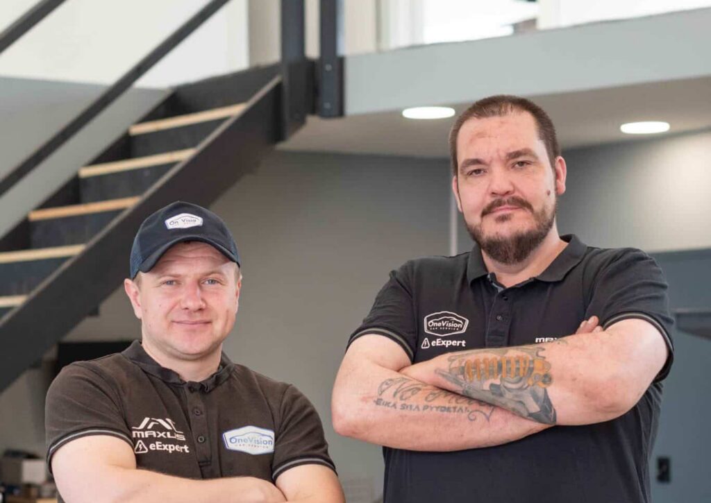 OneVision Car Service autohuolto modernissa autokorjaamossa, taustalla renkaita ja huoltokalustoa.