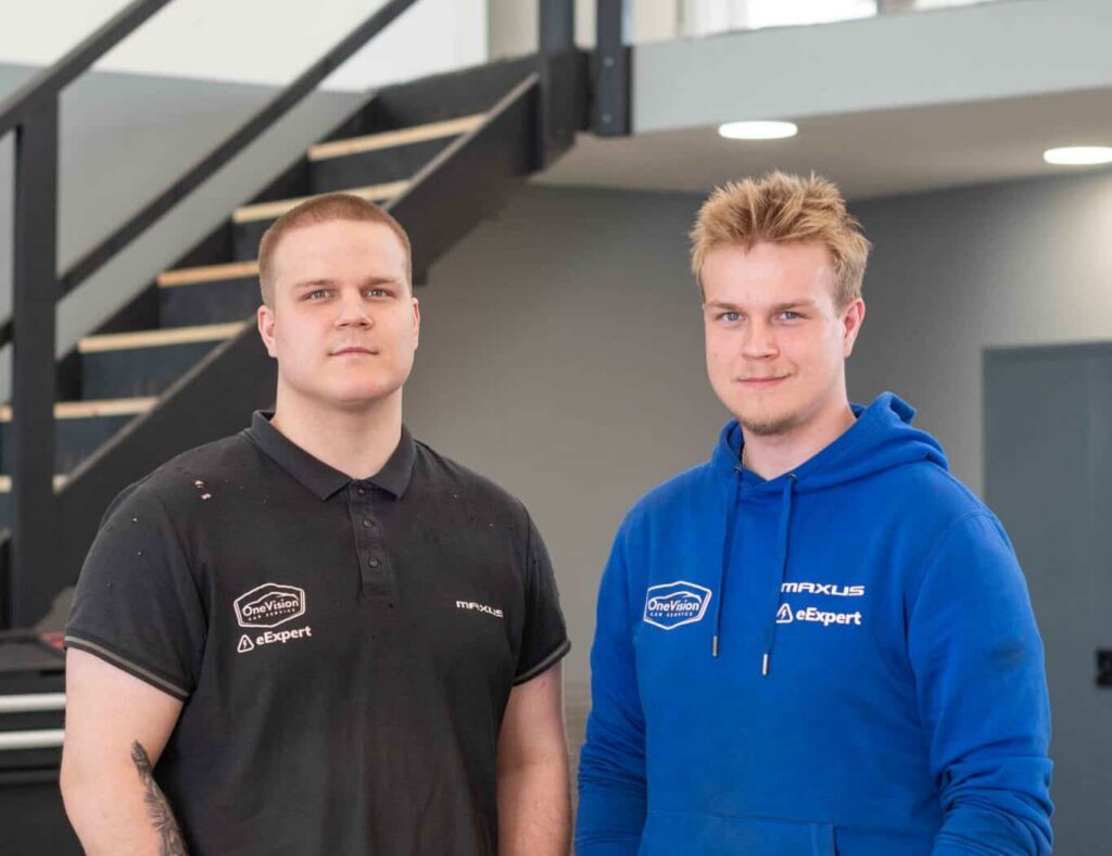 OneVision Car Service autohuolto modernissa autokorjaamossa, taustalla renkaita ja huoltokalustoa.