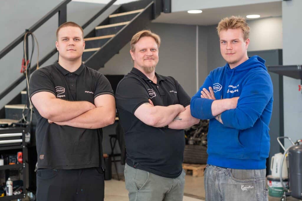 OneVision Car Service autohuolto modernissa autokorjaamossa, taustalla renkaita ja huoltokalustoa.