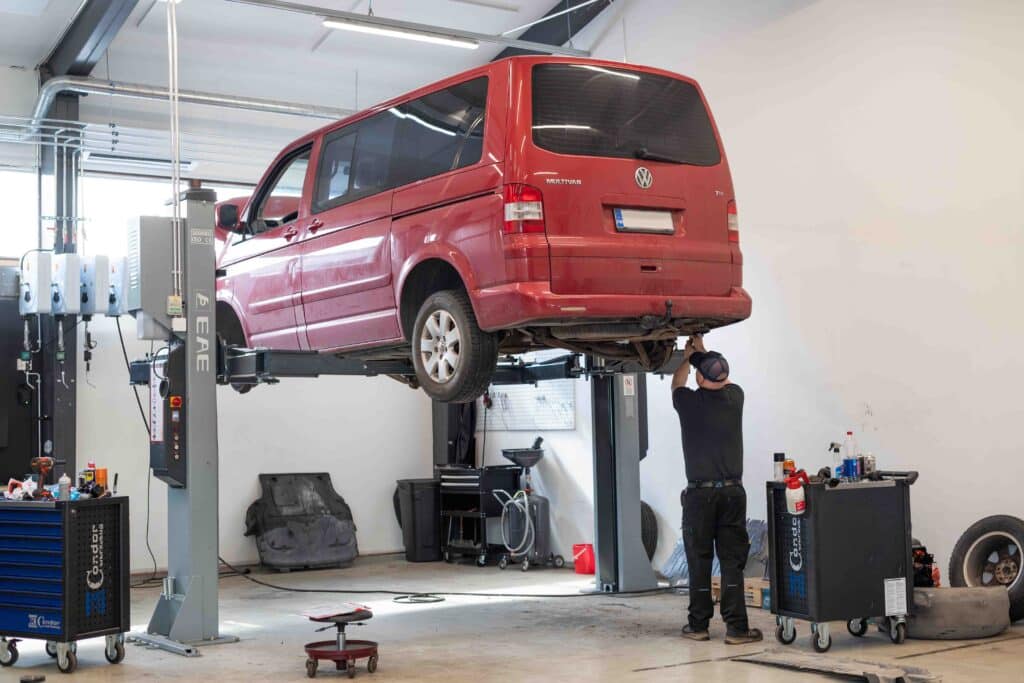 OneVision Car Service autohuolto modernissa autokorjaamossa, taustalla renkaita ja huoltokalustoa.