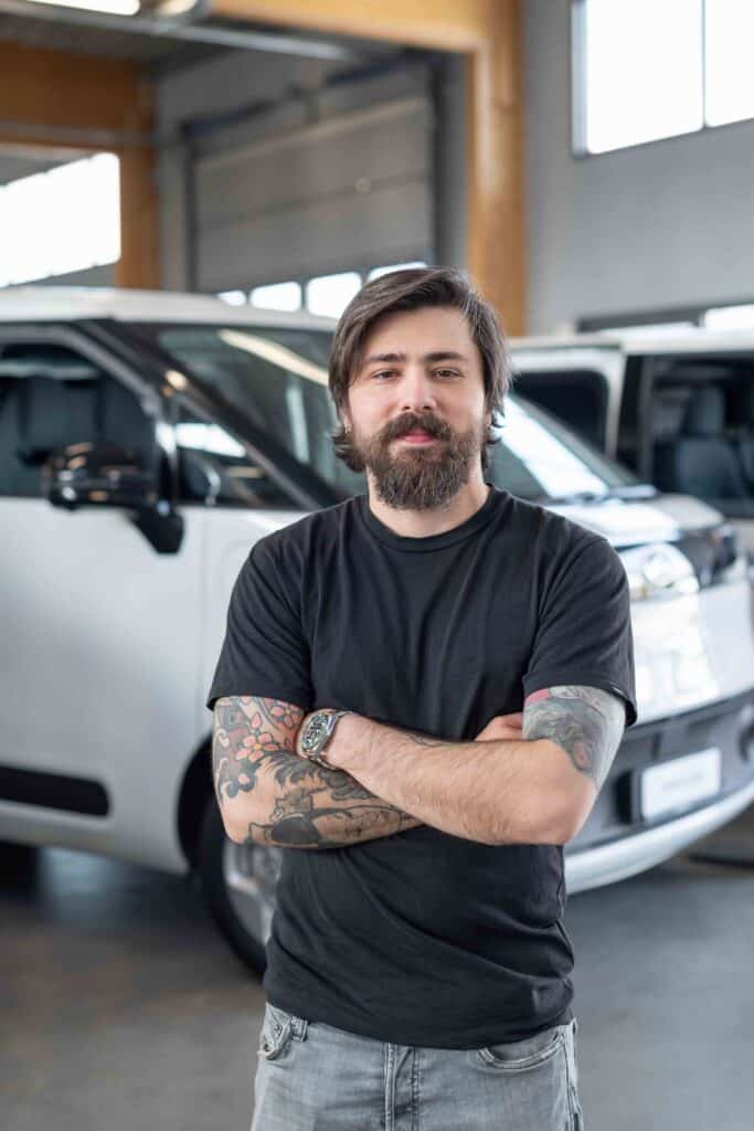 OneVision Car Service autohuolto modernissa autokorjaamossa, taustalla renkaita ja huoltokalustoa.