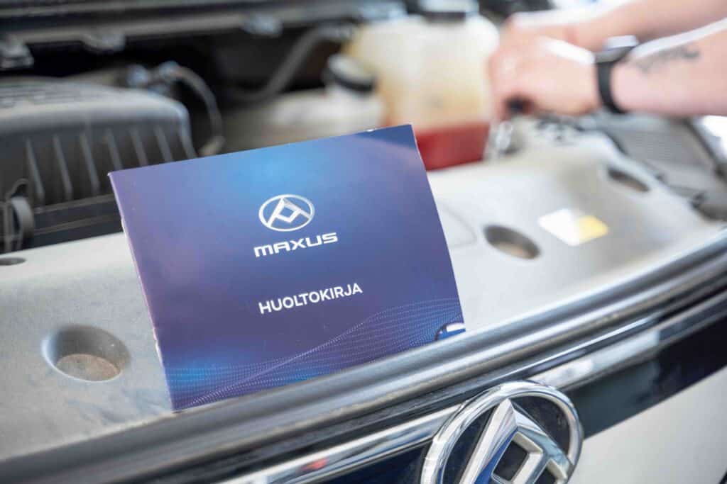 OneVision Car Service autohuolto modernissa autokorjaamossa, taustalla renkaita ja huoltokalustoa.
