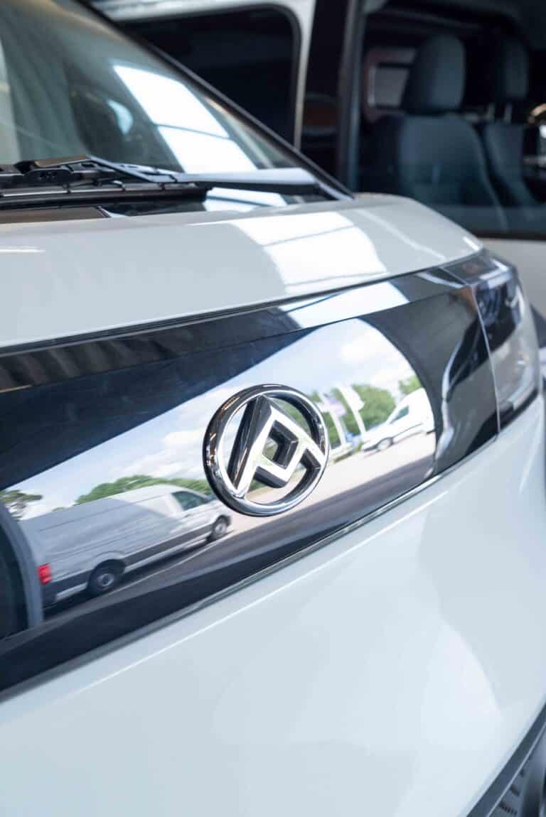 OneVision Car Service autohuolto modernissa autokorjaamossa, taustalla renkaita ja huoltokalustoa.