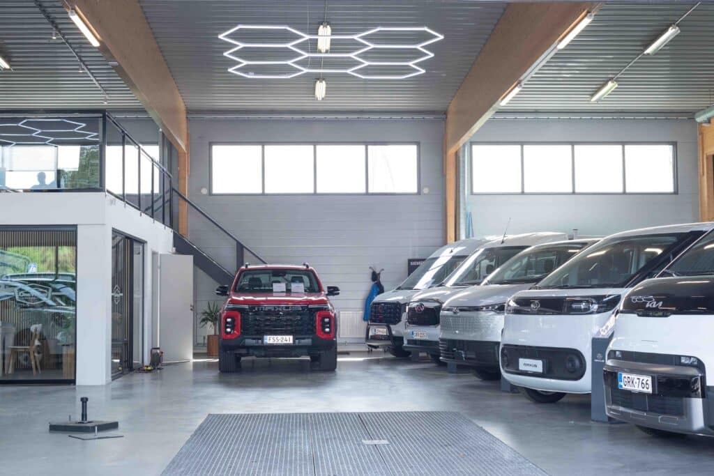 OneVision Car Service autohuolto modernissa autokorjaamossa, taustalla renkaita ja huoltokalustoa.