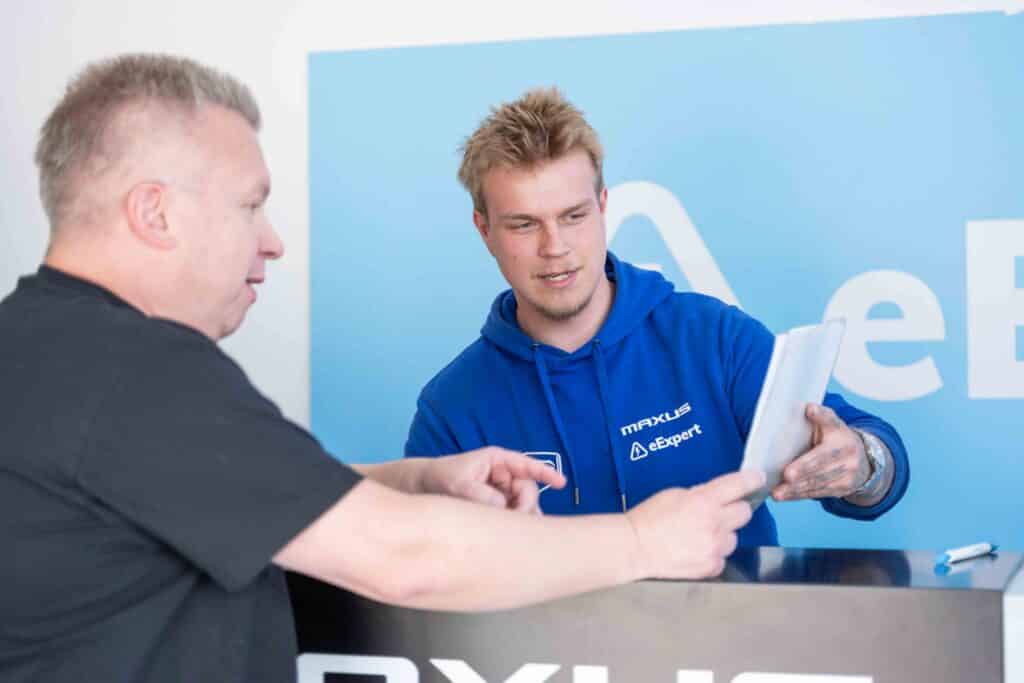 OneVision Car Service autohuolto modernissa autokorjaamossa, taustalla renkaita ja huoltokalustoa.